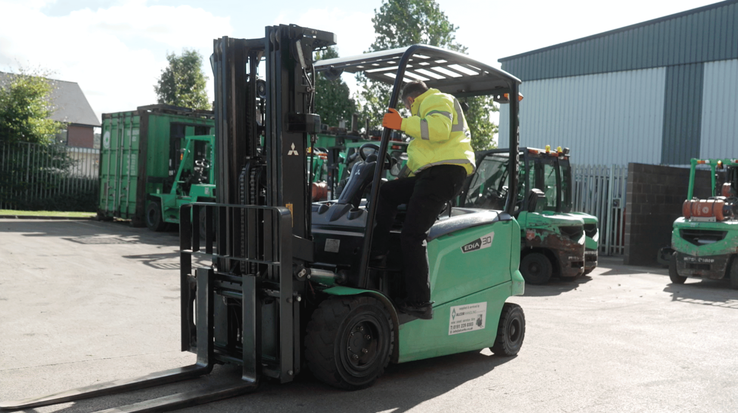 Green Mitsubishi electric forklift in an industrial yard